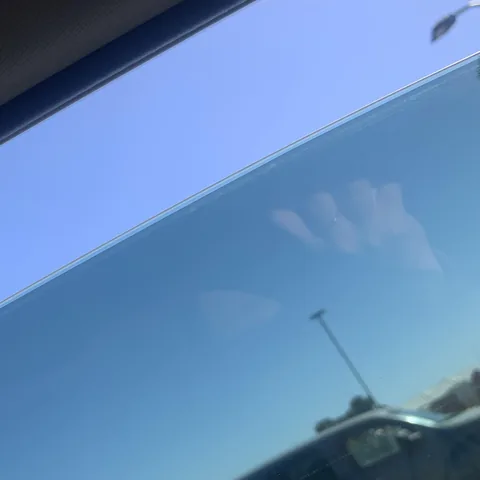 Top edge of a tinted car window with aftermarket film ending just below the edge of the glass