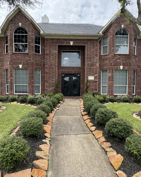 Red brick two-story home with arched upper windows and a tall window above the front doors