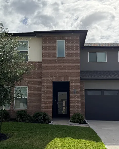 Brick and stucco two-story home with window film on the front windows