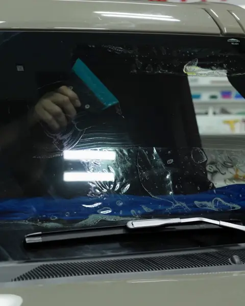 Installer squeegeeing clear heat-rejecting film onto the windshield of a Ford Bronco