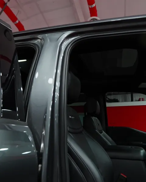 Open doors of a gray Ford Super Duty showing the black leather interior and tinted glass