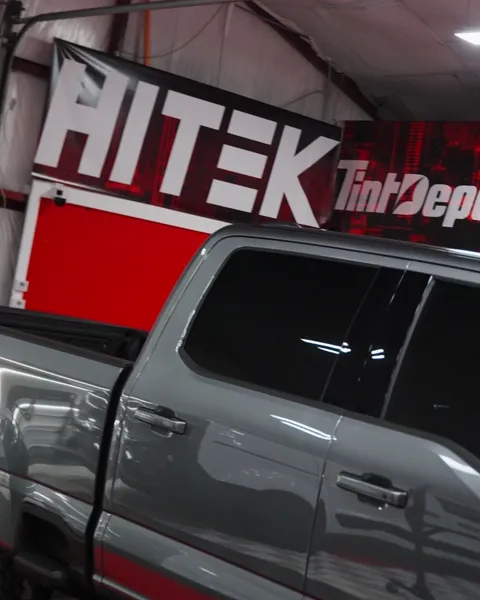 Tinted side windows of a gray Ford Super Duty crew cab in the shop