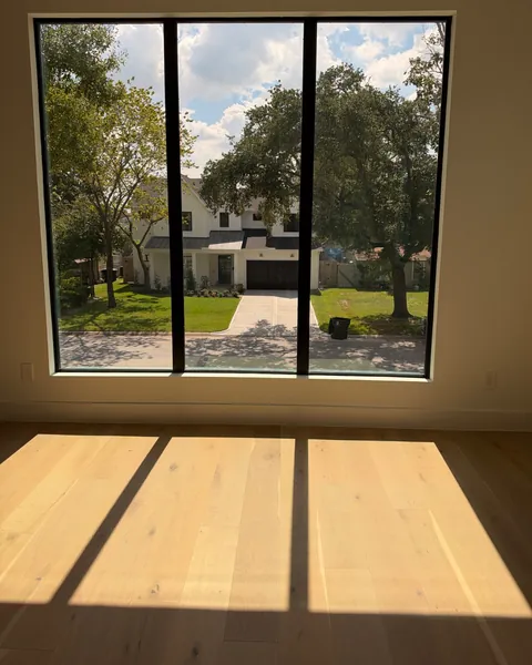 Afternoon sun through a large three-panel window falling across light oak floors