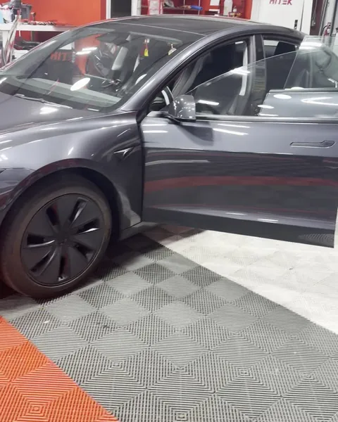 Gray Tesla Model 3 Highland with its driver door open in the Texas Tinted shop